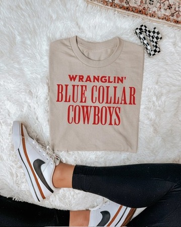 Beige Blue Collar Cowboys graphic T-shirt with red WRANGLIN' BLUE COLLAR COWBOYS lettering.