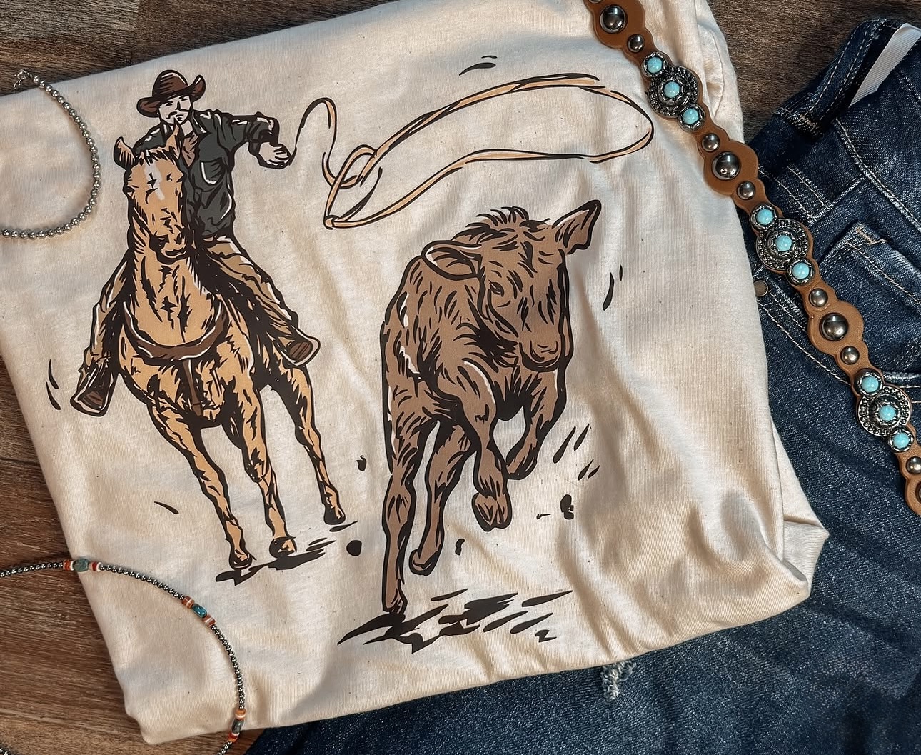 Beige Calf Ropin graphic T-shirt with cowboy roping a calf on horseback.