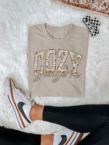 Beige Cozy Season graphic T-shirt with patterned COZY lettering and script season text.